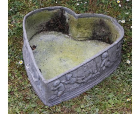 AN ANTIQUE LEAD HEART SHAPED PLANTER the outsides decorated with putti frolicking, 37cm wide x 43cm deep x 12cm high