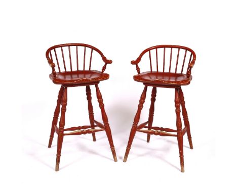A PAIR OF RED PAINTED WINDSOR STYLE OAK HIGH SEATED STOOLS with arching stick backs and turned tapering legs united by stretc