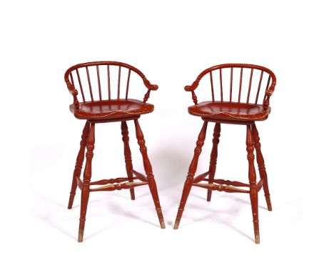 A PAIR OF RED PAINTED WINDSOR STYLE OAK HIGH SEATED STOOLS with arching stick backs and turned tapering legs united by stretc