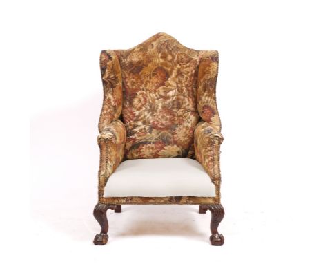 A GEORGIAN TAPESTRY UPHOLSTERED WING ARMCHAIR with camel back standing on ball and claw feet, 118cm high