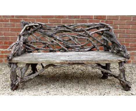 A RUSTIC WOODEN GARDEN SEAT  with intertwined back, 144cm wide x 81cm high