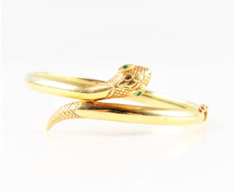 A 14ct yellow gold snake bangle, set with a round cut emerald to each eye, head and tail engraved with scale design, hallmark