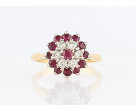 An 18ct yellow gold ruby and diamond tiered cluster ring, set with a central round cut ruby surrounded by a border of round b