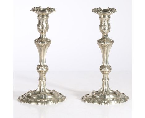 Each with tulip-shaped socket and detachable bobeche, on a baluster-knob stem and circular base, bold Rococo shell, leafy-pet