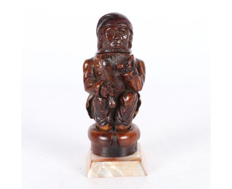 In the form of a gentleman wearing a jacket and smoking a pipe crouched down, raised on a brass and pearl base, 12.5cm high.
