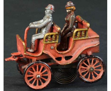 278. KENTON CLOCKWORK RUNABOUT | Early automobile done in a faded red color with gold and black highlights, two seated figure