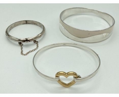 3 silver and silver plated bangles. A child's hinged bangle with diamond cut pattern and safety chain, a white enamel and sil