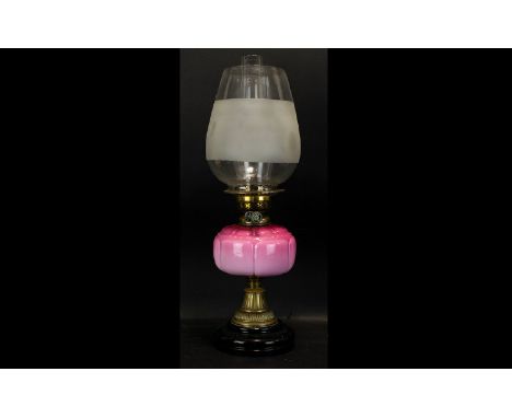 An Early 20th Century Oil Lamp Of Typical form with pink ombre glass reservoir, with brass mounts and black glass base, heigh