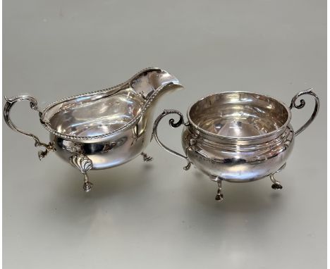 A Birmingham silver George III style, gardroon rimmed bordered, sauce boat in shell cast pad feet, with c scroll handle to si
