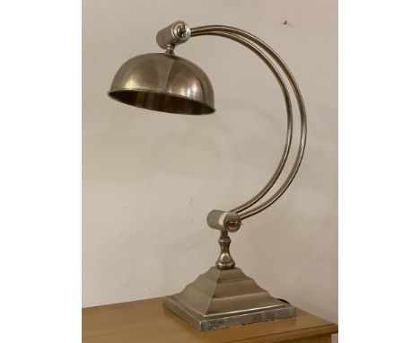 An Art Deco style silvered metal table light, the domed angle adjustable shade over bowed stretchers and a stepped square bas