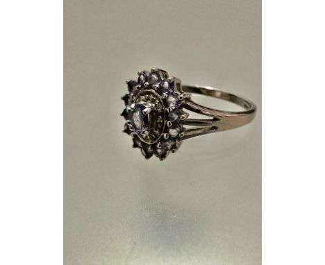 An 9ct white gold pale tanzanite and diamond set cluster ring, the oval centre stone with surround of illusion set diamond ch