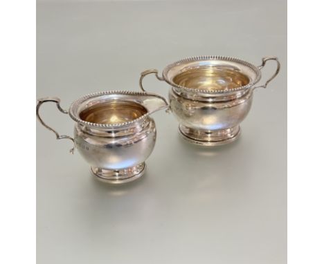 A Birmingham silver two handled sugar basin and creamier with gadroon borders and c scroll handles, (h 7cm x 10cm) Birmingham