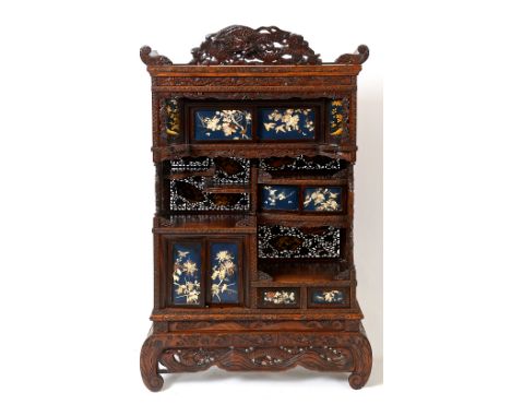 A Japanese cabinet, having an arrangement of sliding doors, drawers and panel doors, carved and pierced all over with dragons