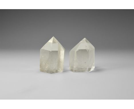 A group of two quartz crystals with polished faces, each with internal veils and bubbles, some of which have rainbow reflecti