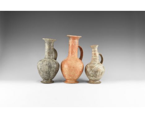 12th-6th century BC. A mixed group of ceramic jugs comprising: one burnished red slip ware with everted rim and base, bands o