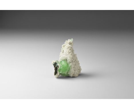 A group of green apophyllite crystals resting on a bed of tiny white crystals, overlain with several blades of scolecite, in 