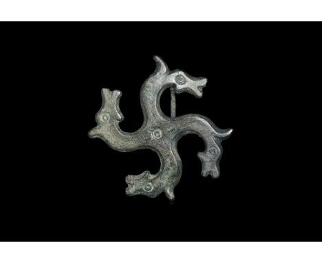 2nd century AD. A bronze plate brooch formed as four profile horse-heads radiating from a central ring-and-dot, each with rin