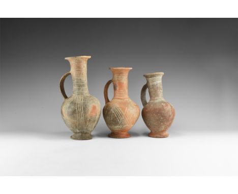 12th-6th century BC. A mixed group of unburnished ceramic jugs, each a bulbous body with flared base and rim, strap handle, w