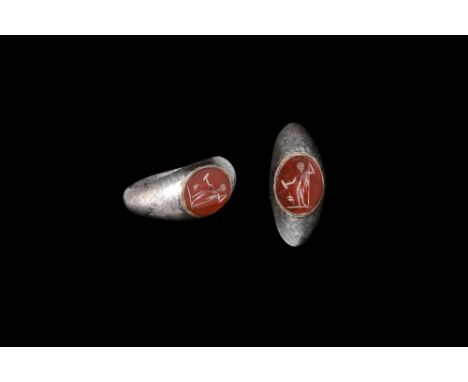 3rd century AD. A D-section silver hoop with expanding keeled shoulders, flat plaque with inset carnelian cloison, intaglio s