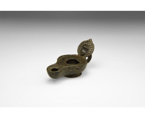 2nd century AD. A bronze figure-of-eight lamp with flared base, lip to the upper face, loop handle to the rear, discoid refle