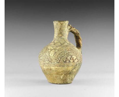 2nd millennium BC. A piriform ceramic jug with tall tubular neck, braided handle with thumb-pad; painted with black check pan