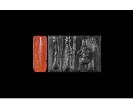7th-6th century BC. A carved carnelian cylinder seal with frieze of three figures: two men in long robes carrying spears befo
