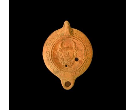 2nd century AD. A terracotta oil lamp with broad face, short nozzle, pierced lug handle; band of stamped horseshoes to the sh
