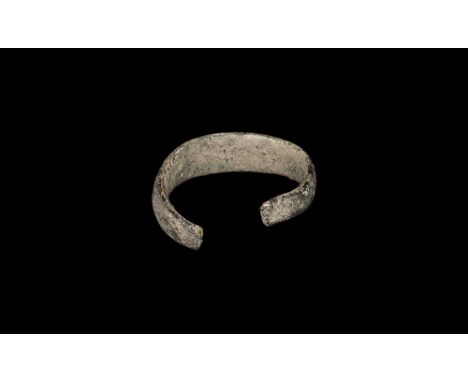 6th century AD. A torc-shaped bracelet with narrow terminals expanding towards the centre.  65 grams, 64.59mm (2 1/2"). Ex Ha