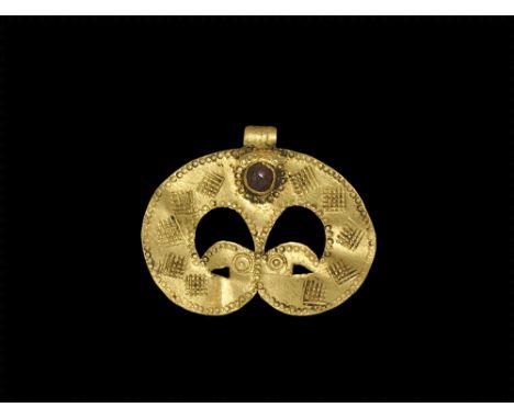 6th-7th century AD. A flat-section gold crescentic plaque with integral ribbed loop, red glass cabochon in cell, addorsed bir
