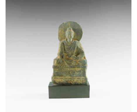 2nd-4th century AD. A carved schist figure of Buddha seated cross-legged on a dais with nimbus to the rear of the head, right