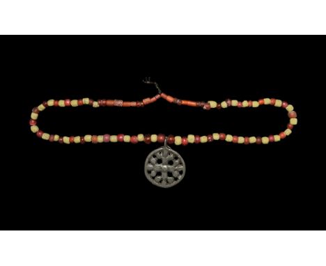 11th century AD and later. A silver coloured pendant with cross botany motif, on a restrung necklace of mainly spherical glas