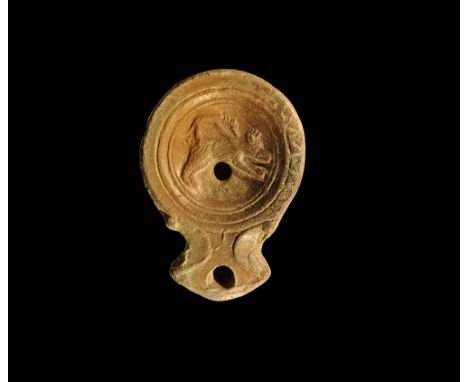 2nd century AD. A shallow terracotta oil lamp with round discus, volute-scrolls to the nozzle with crescentic outer edge; dis