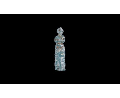 1st-2nd century AD. An iridescent green glass figurine of Venus standing with her upper body exposed, robe draped from her hi