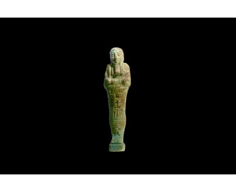 Ptolemaic Period, 305-30 BC. A pale blue and olive glazed composition shabti with tripartite wig, false beard, tools in the c