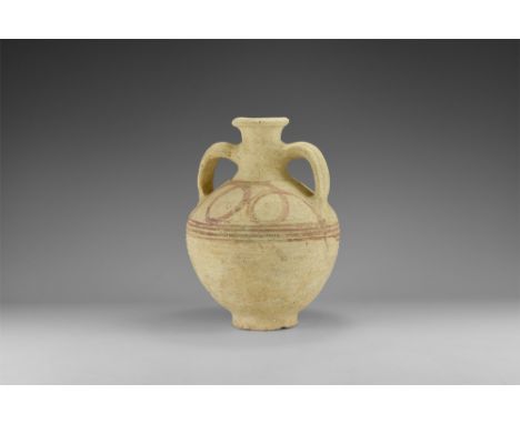 Late 1st millennium BC. A globular ceramic jar with basal ring, ribbed band to the equator, broad shoulder, trumpet-shaped ne