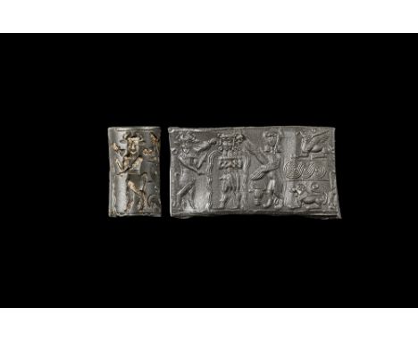 18th-17th century BC. A carved haematite cylinder seal with a central motif of a standing young male holding a cup with two f