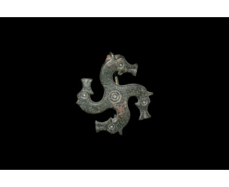 2nd century AD. A bronze plate brooch formed as four profile horse-heads radiating from a central ring-and-dot, each with rin