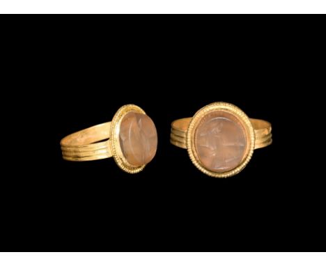1st century AD. A flat-section gold hoop with circumferential ribbing, discoid plaque with beaded wire edge, inset banded aga