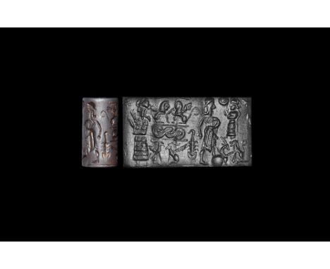 18th-17th century BC. A carved haematite cylinder seal with three figures, central small female figure standing on a lion wit
