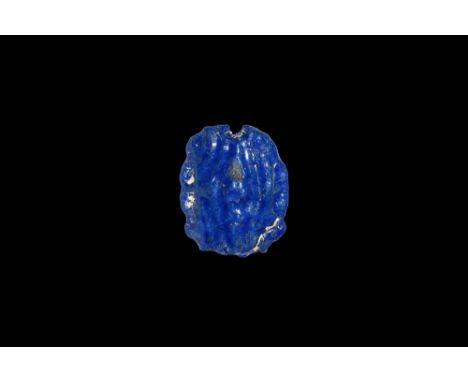 Amarna Period, 1353-1336 BC. A deep blue glazed composition amuletic bead, four wedjat motifs around a central lotus flower. 