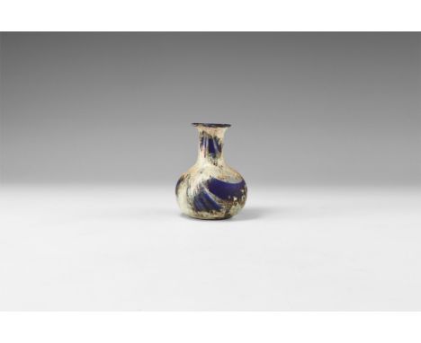 3rd-4th century AD. A bulbous blue glass bottle with iridescent marbling, dimple base, tubular neck, flared rim. Cf. Whitehou