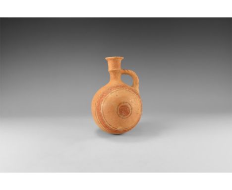 12th-10th century BC. A terracotta globular flask with trumpet -shaped neck with median carination, everted rim, bifid strap 