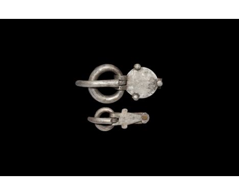 5th-7th century AD. A mixed pair of silver belt buckles comprising: a large discoid plaque with three substantial rivets atta