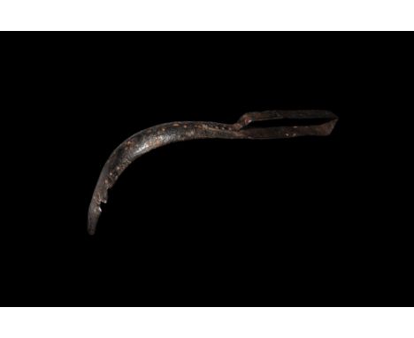 1st-2nd century AD. An iron strigil with right-angle curved C-section blade, narrow handle with leaf-shaped finial fixed to t
