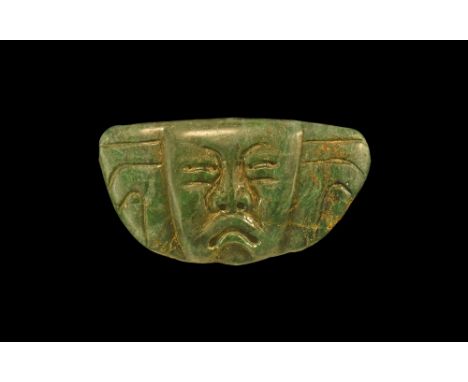 1st millennium BC. A carved jadeite D-shaped panel with holes to the upper and lateral edges; to one face a facing mask with 