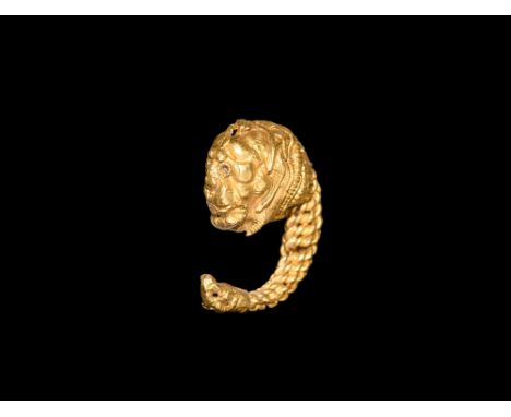 5th-3rd century BC. A hollow-formed gold earring comprising: a lion mask with beaded wire collars to the eyes and neck, roset