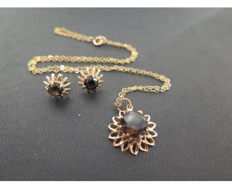 A 9ct gold smokey quartz flower pendant - Hallmarked London - Length 2.5cms - Suspended from a belcher-link chain - Stamped 9
