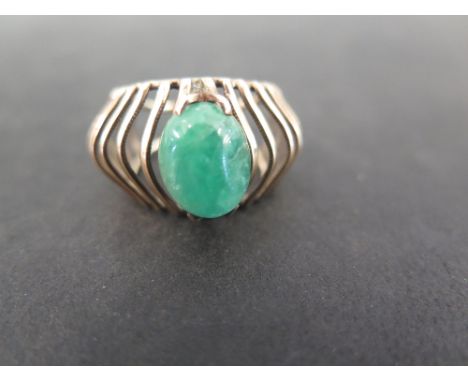 An abstract emerald dress ring - The oval emerald cabochon to the 'cage-like' surmount and openwork band - Tests as 9ct gold 