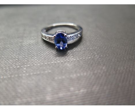 A 9ct gold tanzanite and diamond dress ring - The oval-shape tanzanite to the brilliant-cut diamond shoulders and plain band 