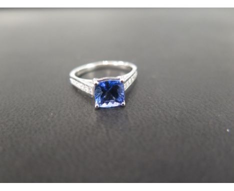 An 18ct gold tanzanite and diamond dress ring - The cushion-cut tanzanite to the brilliant-cut diamond channel-set shoulders 